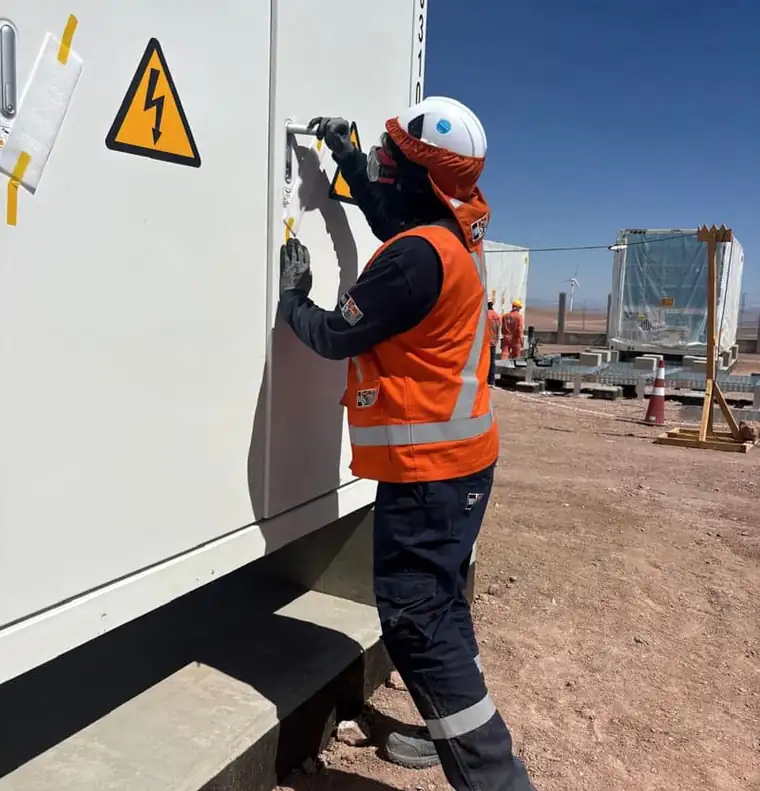 Técnico con equipo de protección personal revisando un gabinete eléctrico en terreno